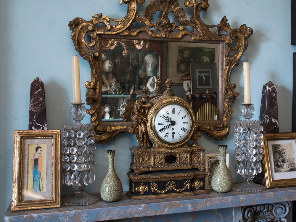 A period interior with gilt mirror, mantel clock and pictures